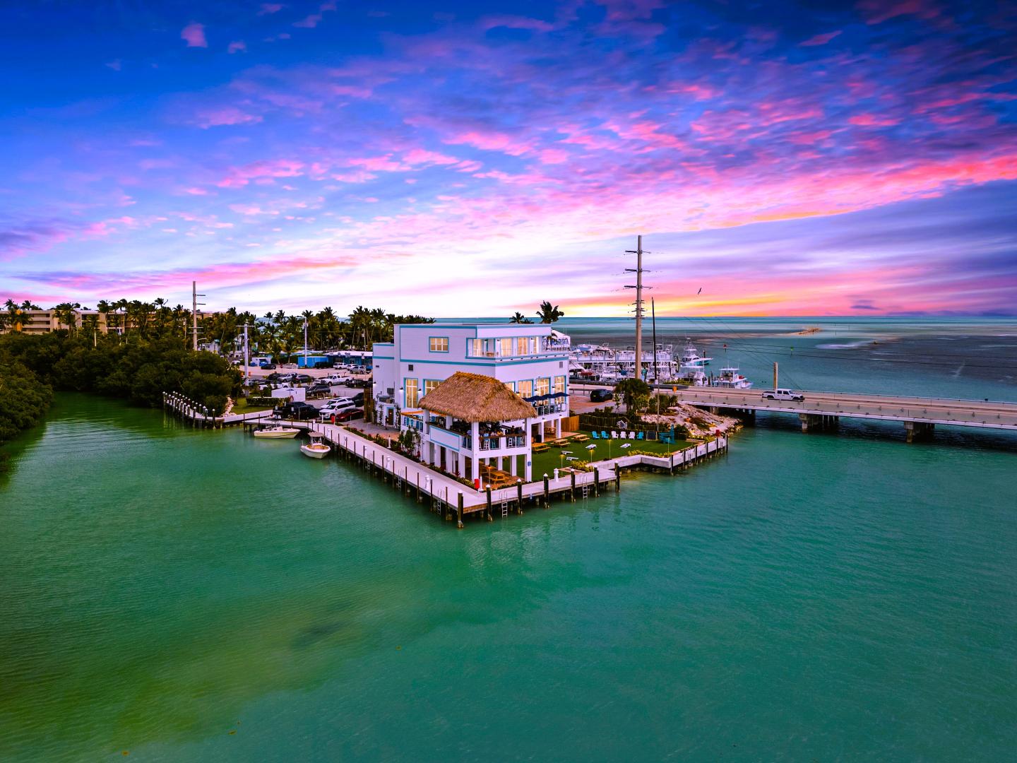 Tropical seaside house at sunset with vibrant pink and purple sky.