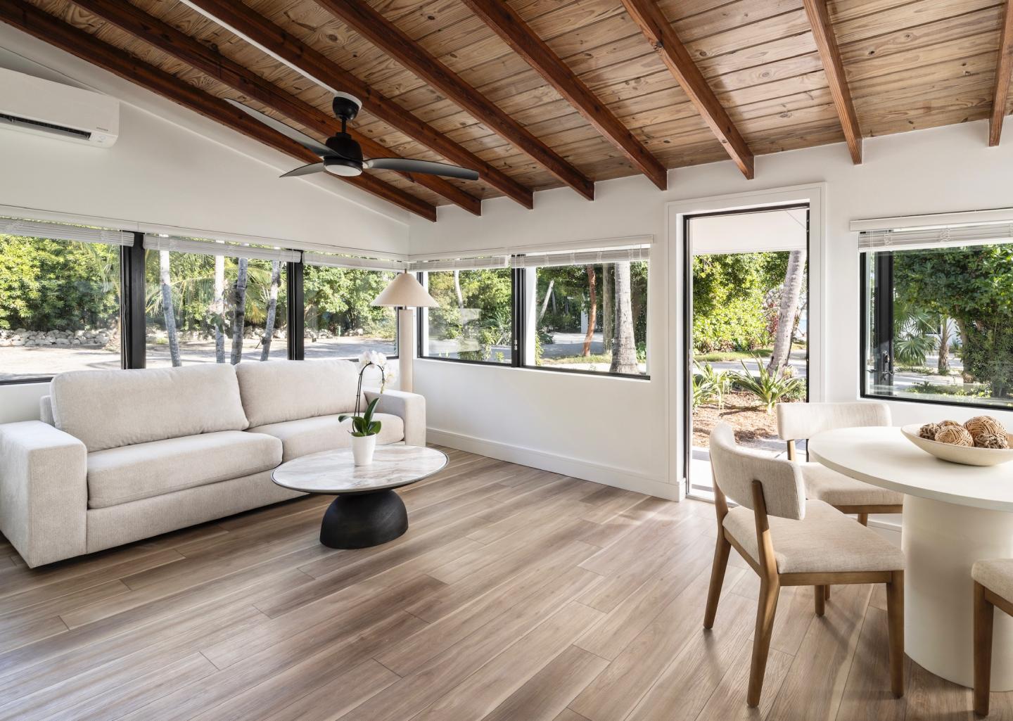 Spacious living room with white sofa, round table, and large windows.