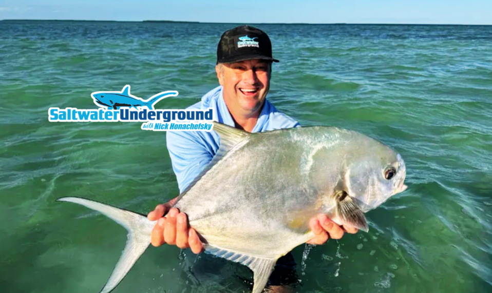 Man smiling, holding a large fish in the sea near "Saltwater Underground" logo.
