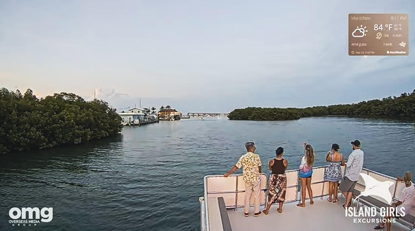 Group on a boat, viewing a tranquil river and distant trees.