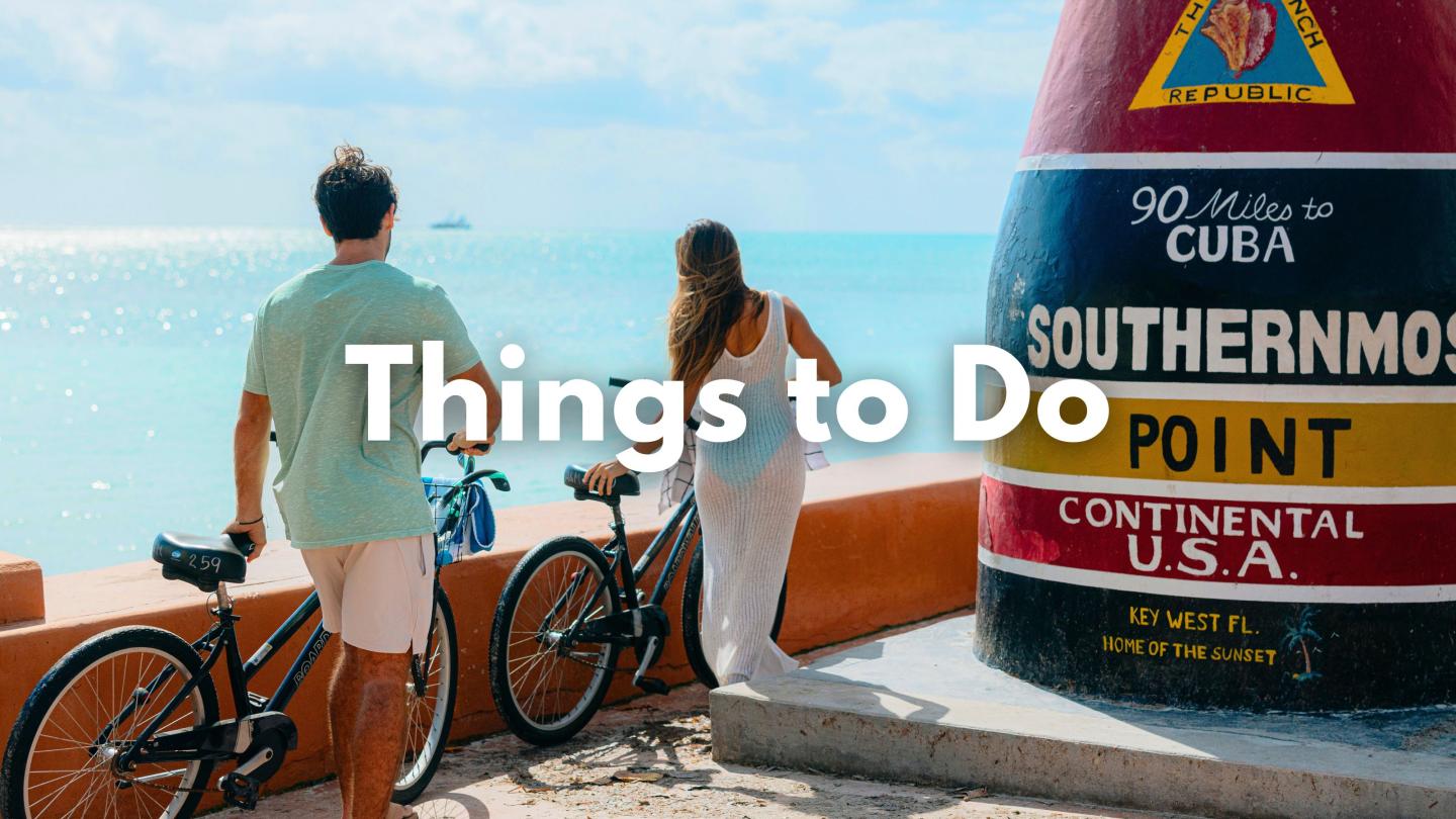 Couple with bikes near a colorful buoy by the ocean.