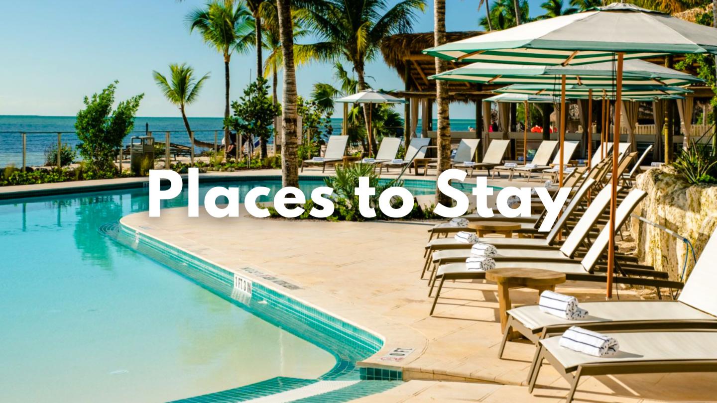 Poolside chairs under umbrellas by the ocean, sunny day.