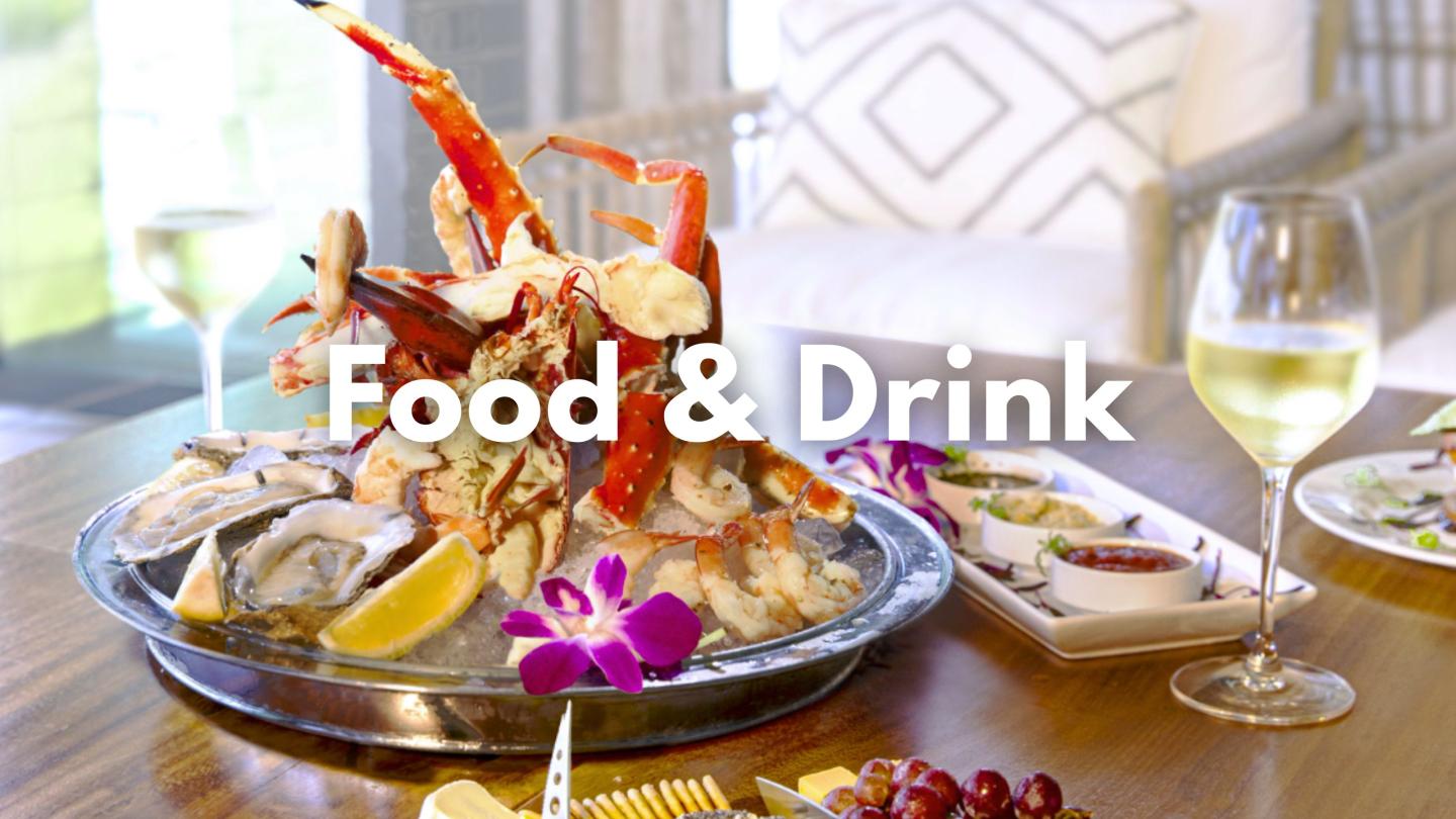 Seafood platter with crab, oysters, lemon, wine, and bright orchid garnish.