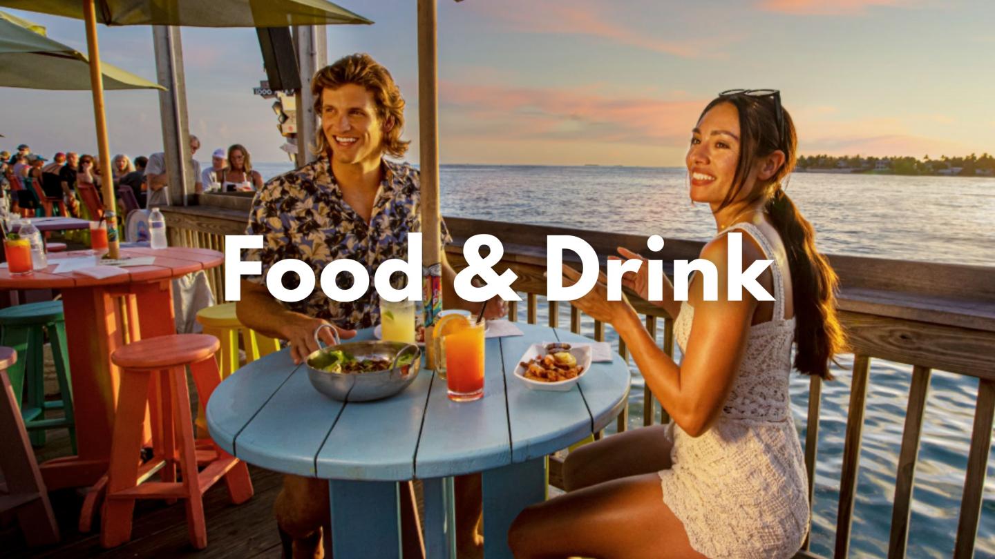 Couple dining outdoors at sunset overlooking the ocean.