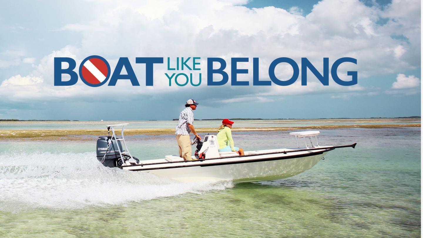 Two people in a boat on clear, shallow water under a cloudy sky.