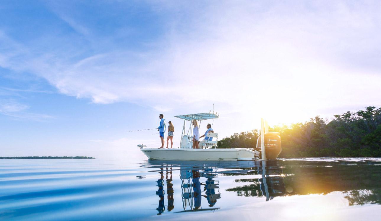 Boat on calm water at sunrise with people standing on deck.