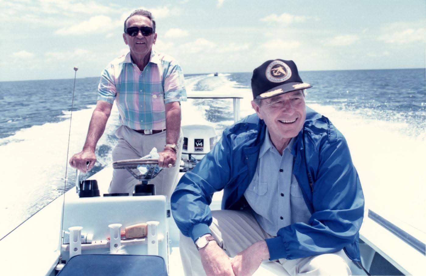 Two men boating on the ocean, one steering, both smiling and relaxed.