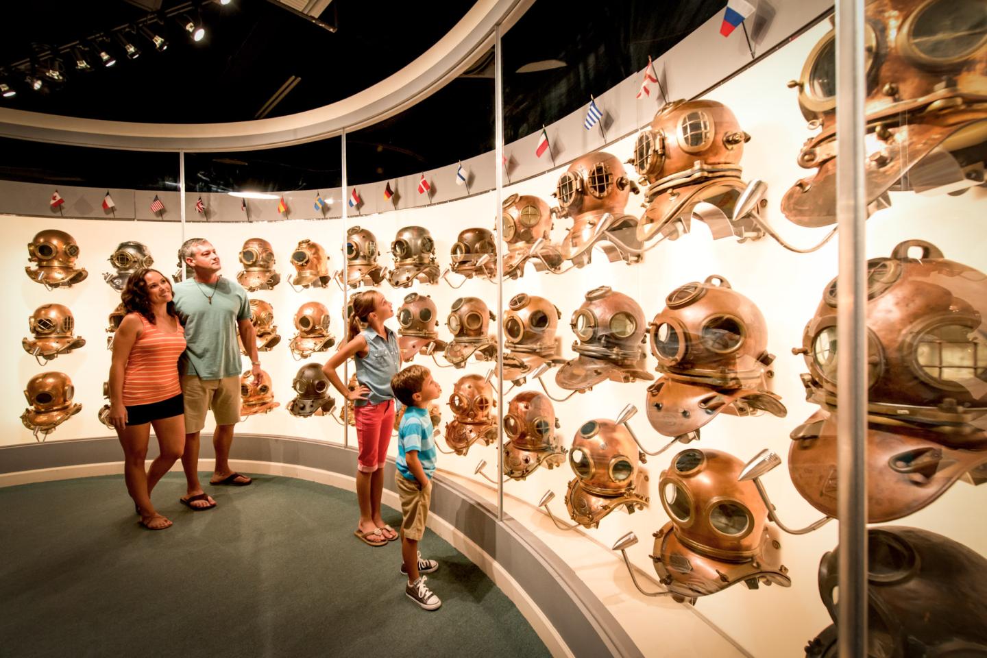 Family viewing vintage diving helmets in a museum exhibit.