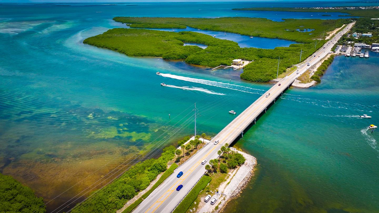 Aerial view of a bridge over turquoise water with green islands.