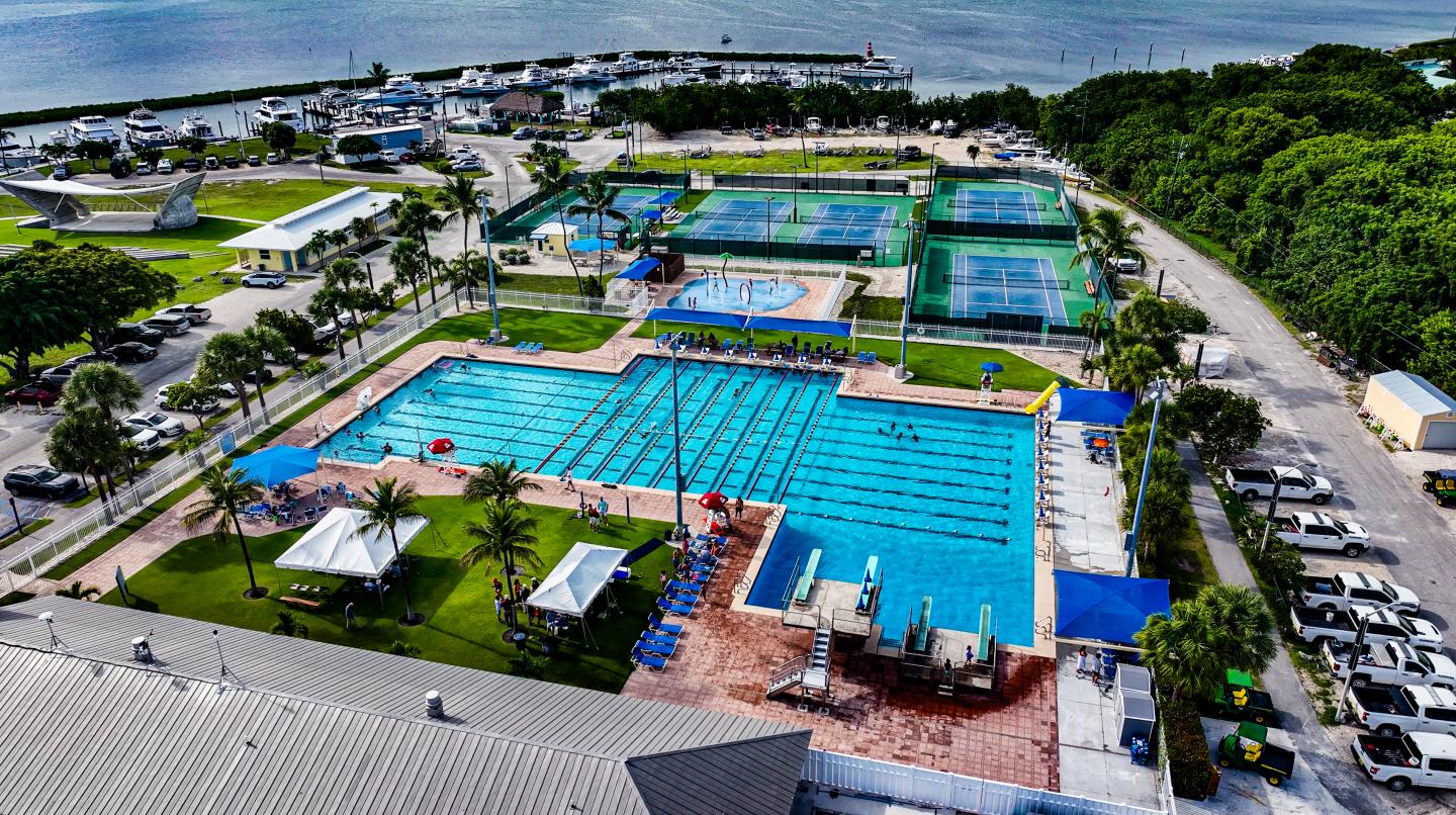 Aerial view of a large outdoor swimming pool complex by the ocean.
