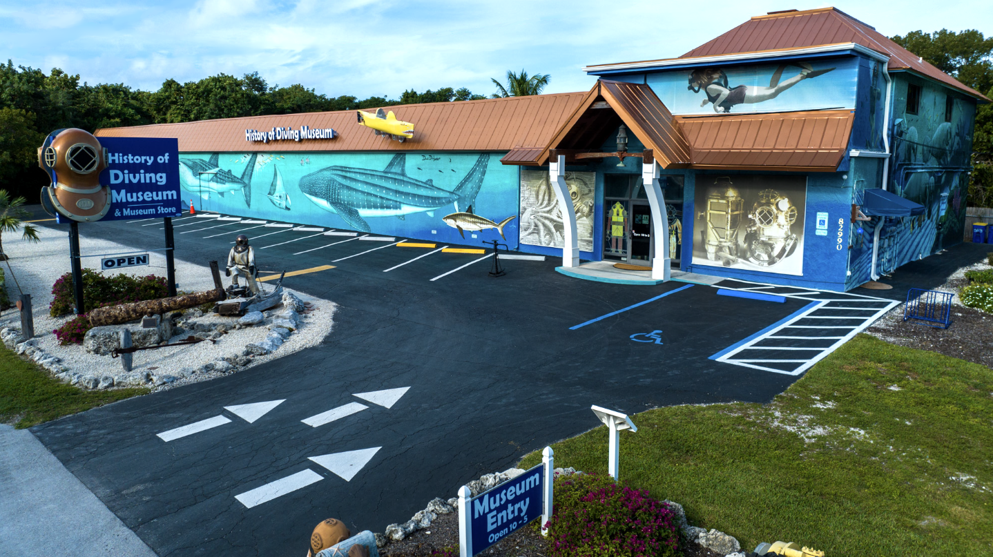 Colorful museum exterior with aquatic mural and directional signs to parking.