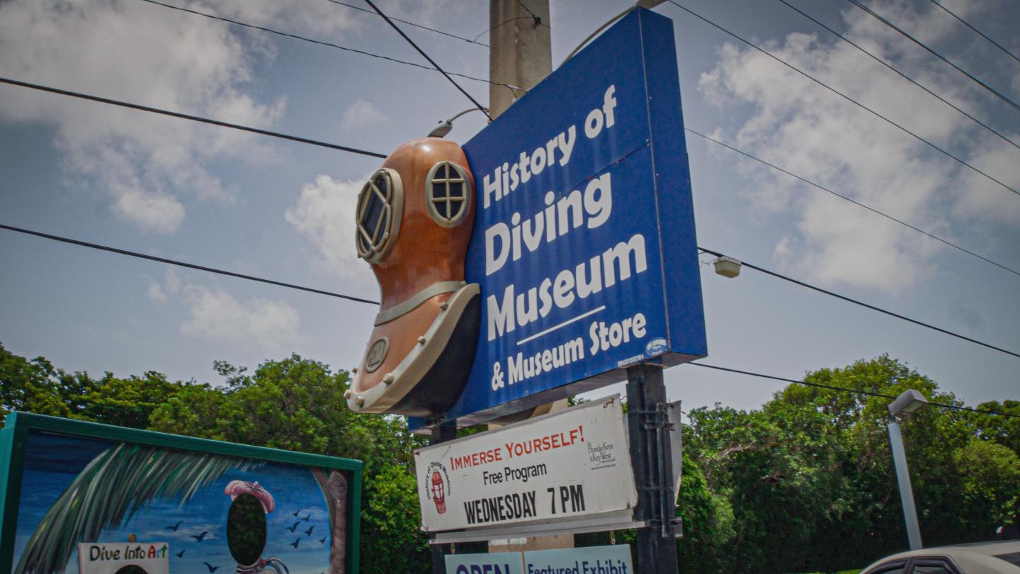 History of Diving Museum sign with diving helmet, blue sky.