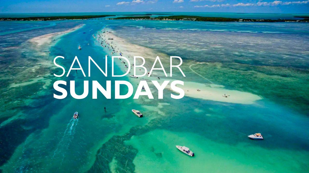 Aerial view of boats near a sandbar in turquoise water.