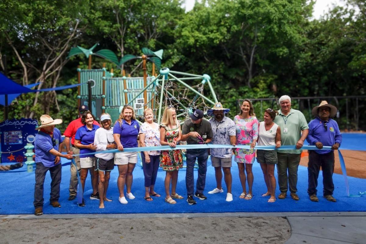 Group cutting ribbon at playground opening event.