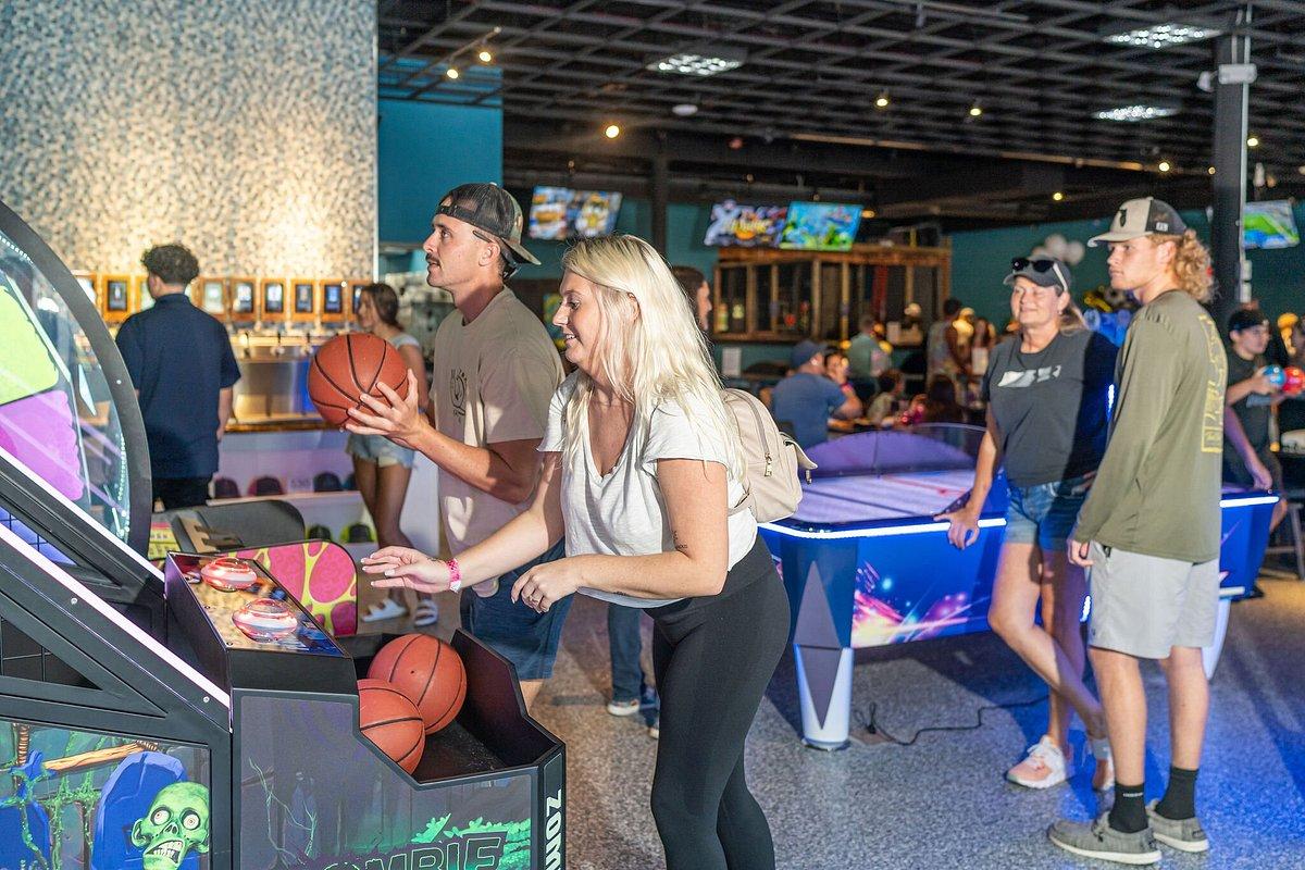 Arcade scene with people playing basketball and air hockey games.