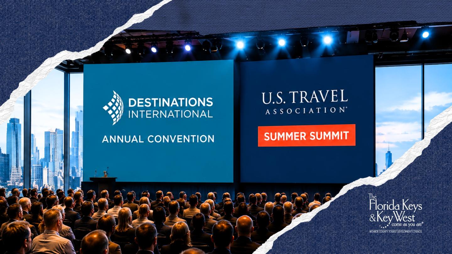Large conference with two screens displaying event titles, audience seated, city skyline visible.
