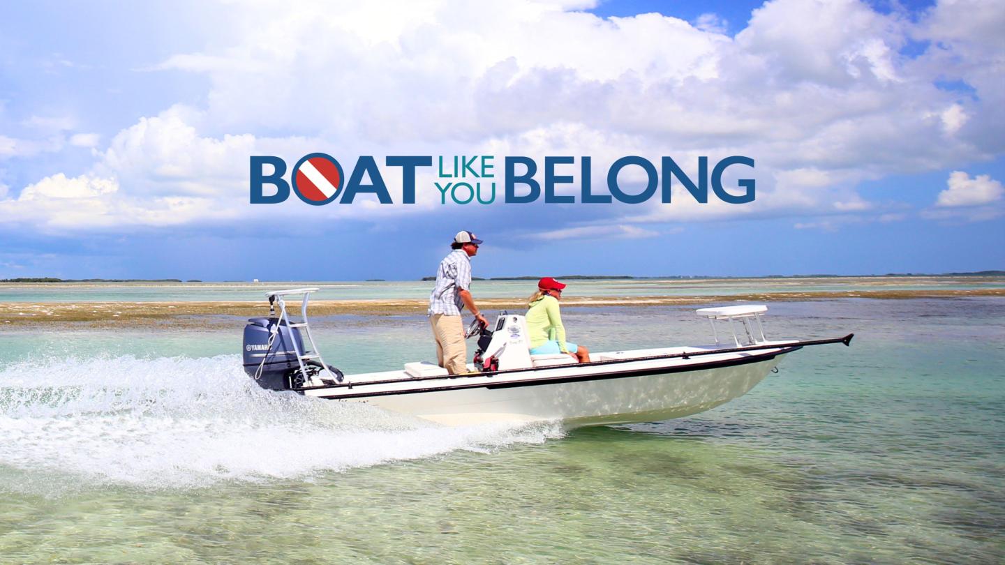 A small motorboat glides on clear turquoise water under a bright blue sky.