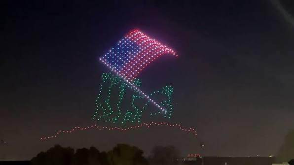 Colorful drones form a flag and figures in the night sky.