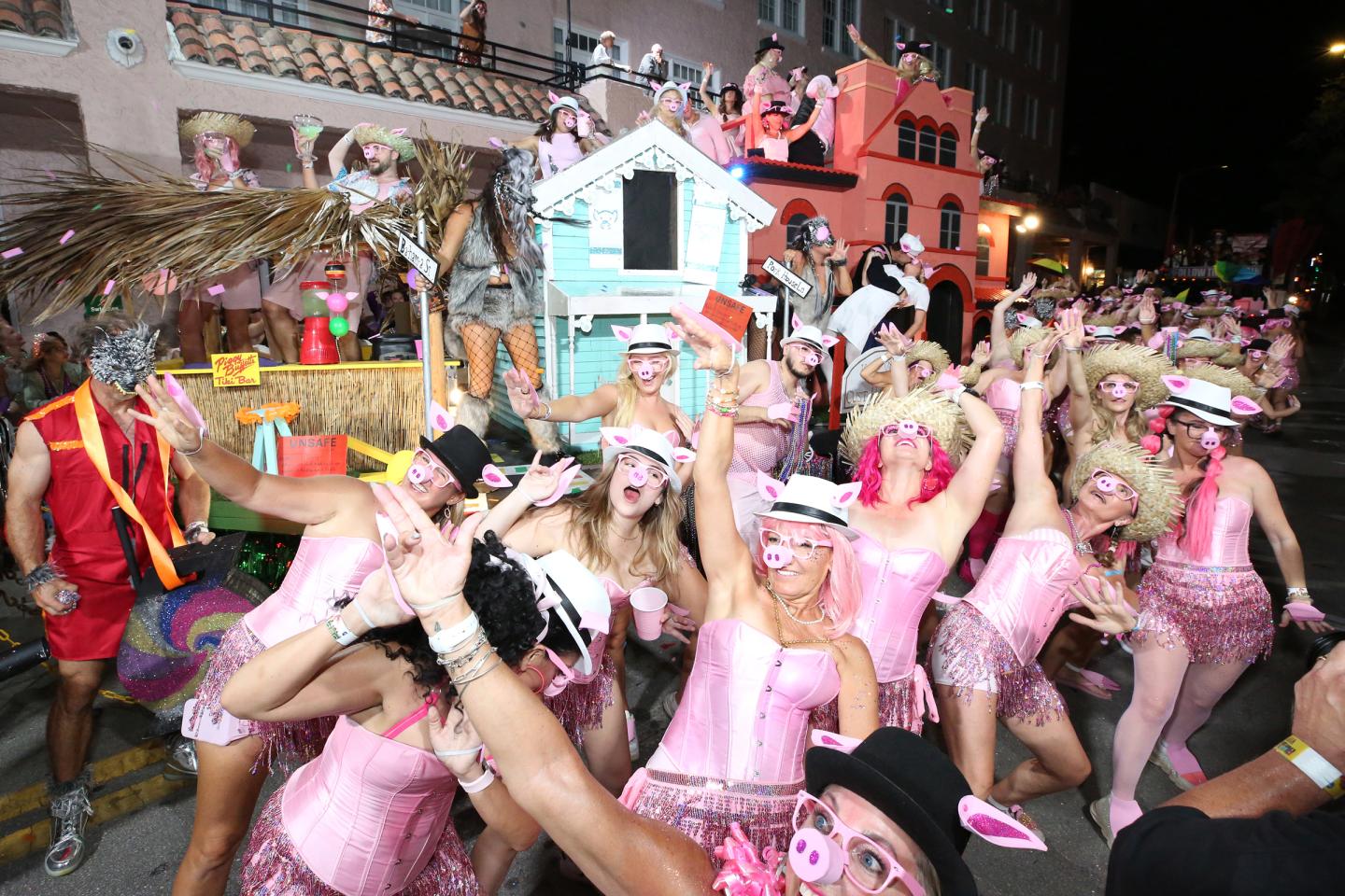 Crowd in pink costumes celebrating at a nighttime street festival.