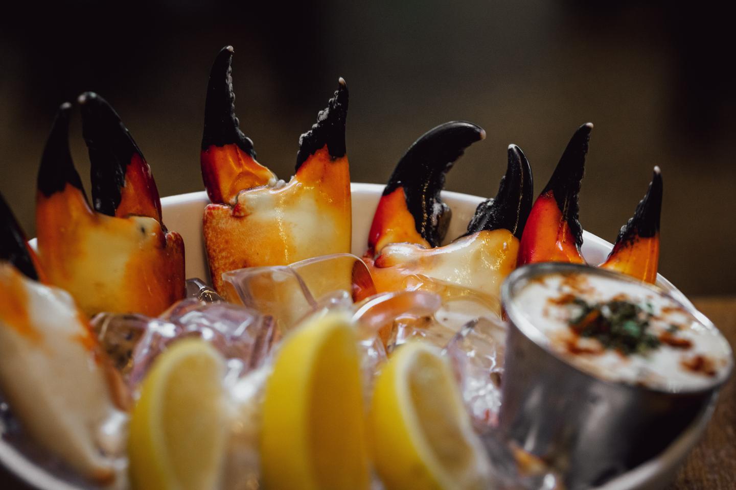 Spoonfuls of seafood salad with lemon wedges, orange slices, and black garnish.
