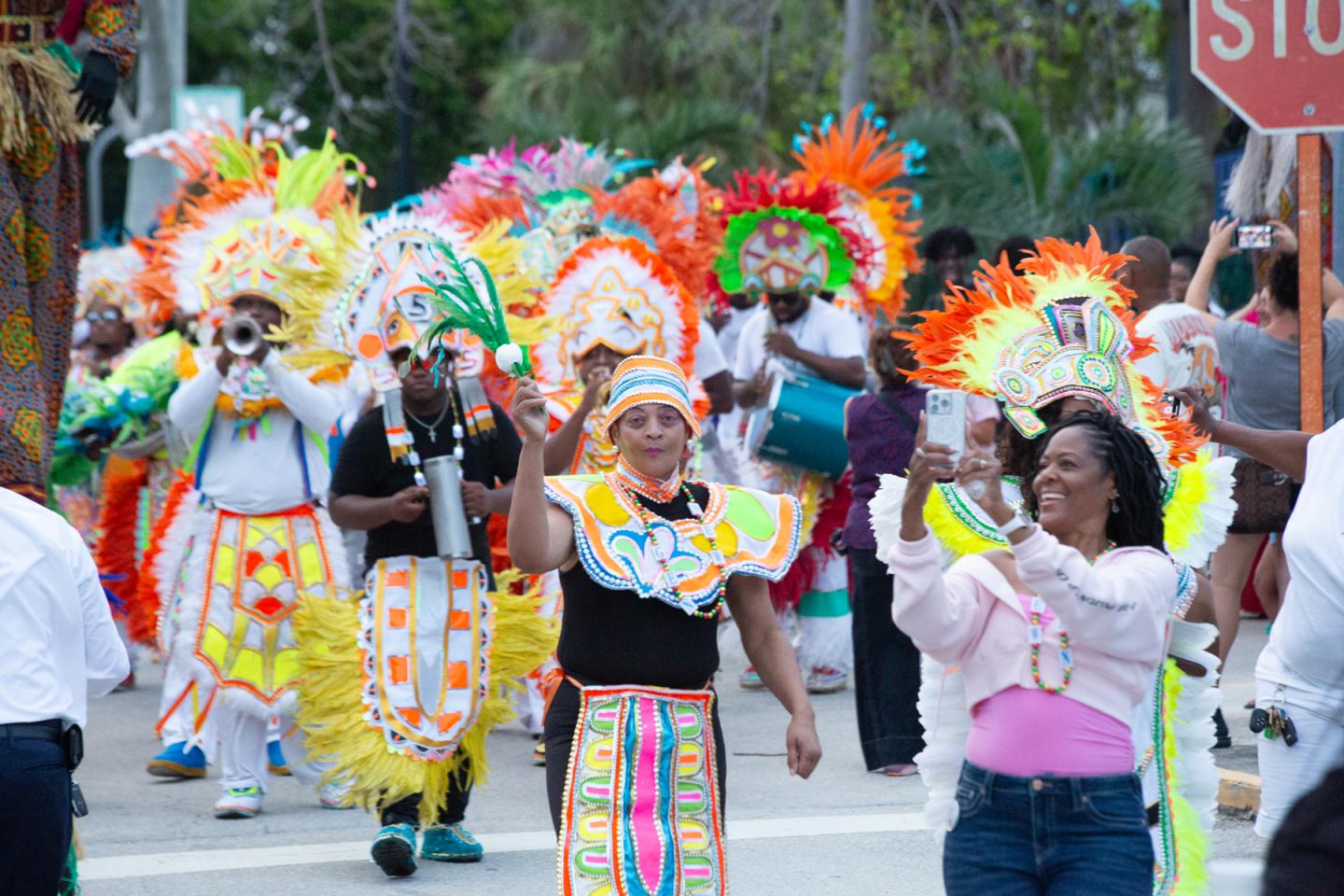 Colorfully costumed dancers parade down a city street.