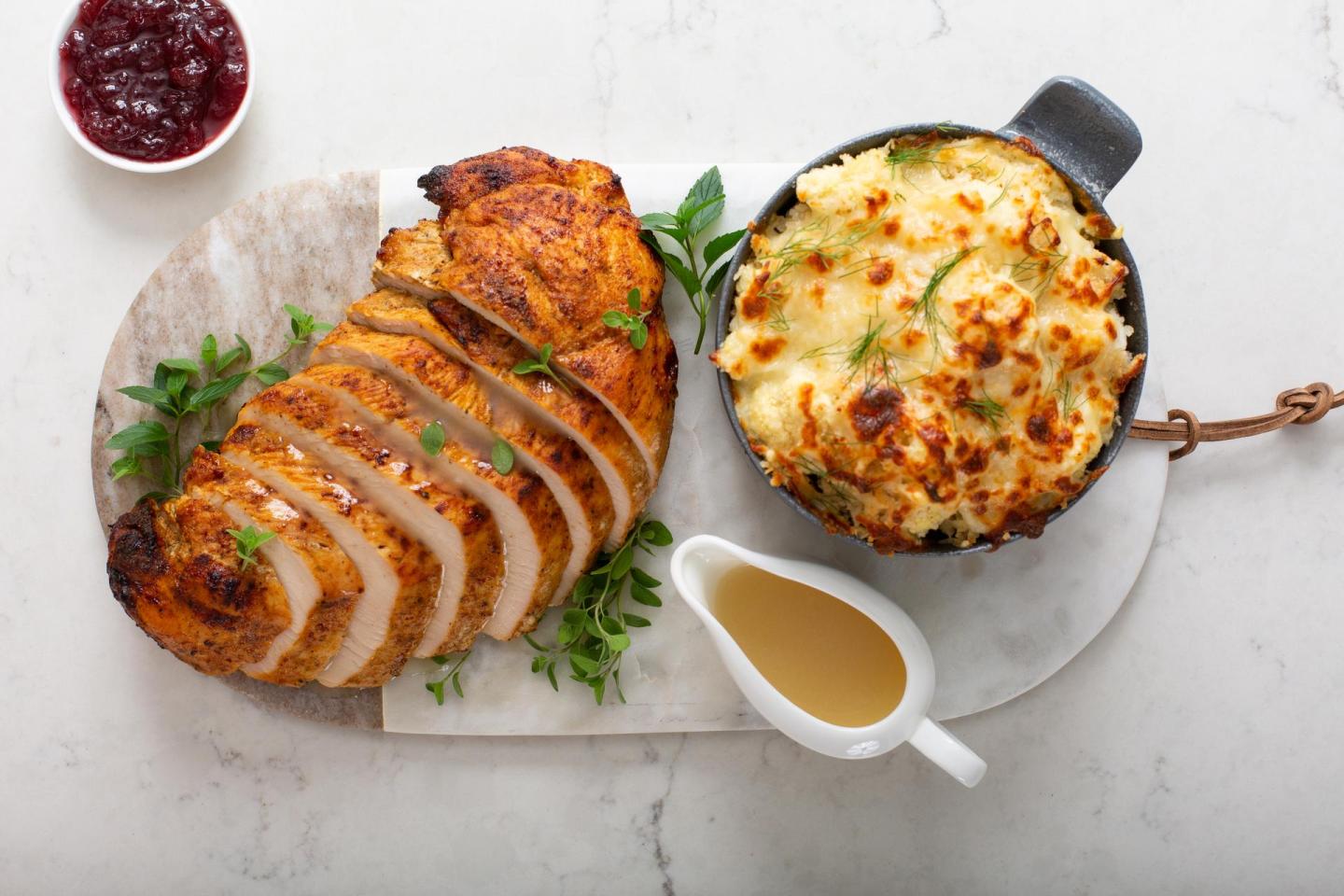 Sliced herb-crusted roast with cauliflower gratin, gravy, and cranberry sauce