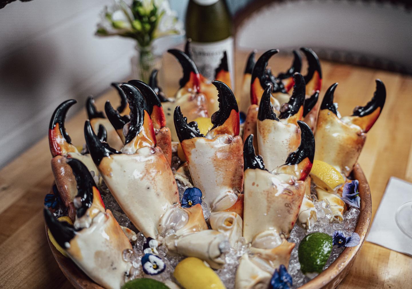 Platter of oysters on ice with lemon wedges and dark crab claws