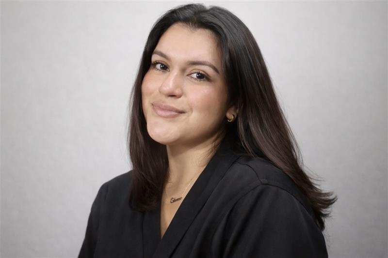Portrait of a smiling woman with long dark hair wearing a black top.