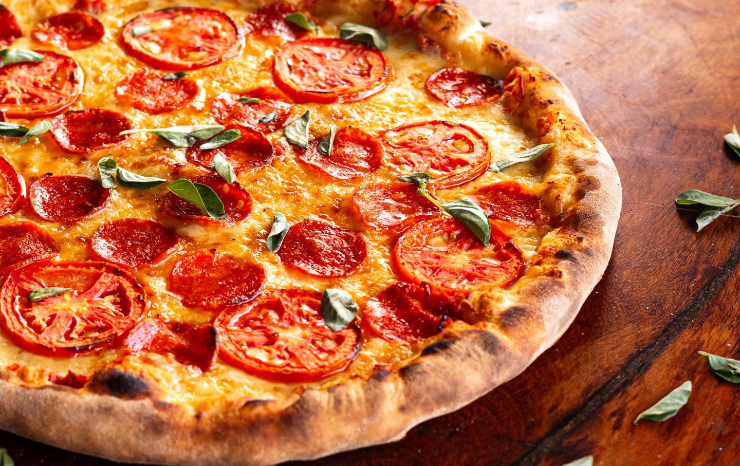Freshly baked pizza topped with tomatoes, pepperoni, basil, and melted cheese