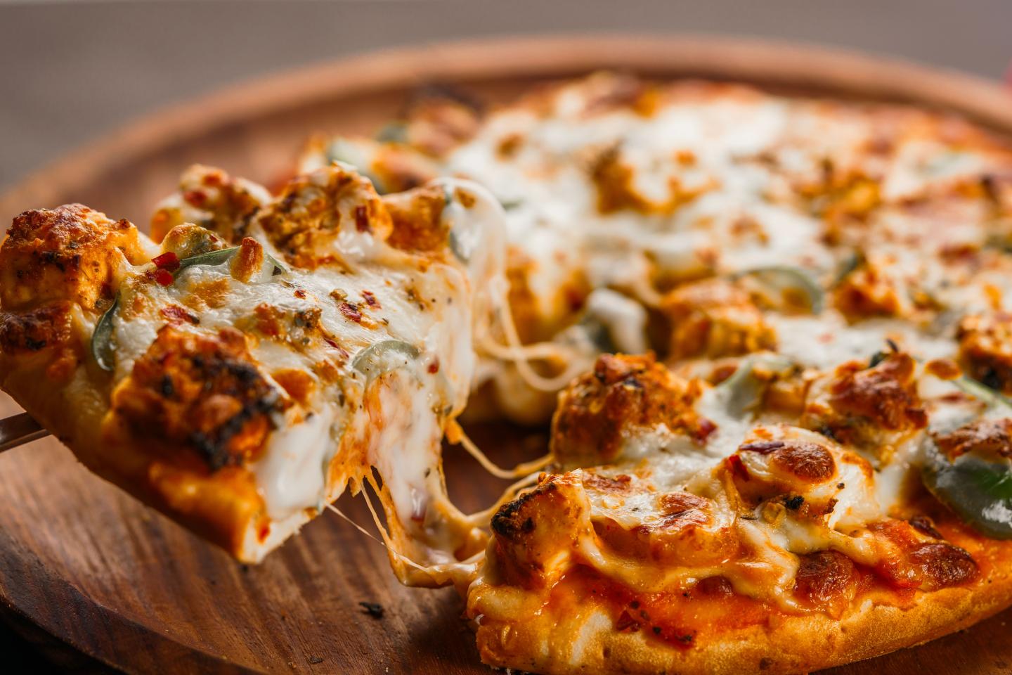 Cheesy pizza slices with sausage and herbs on a wooden board.