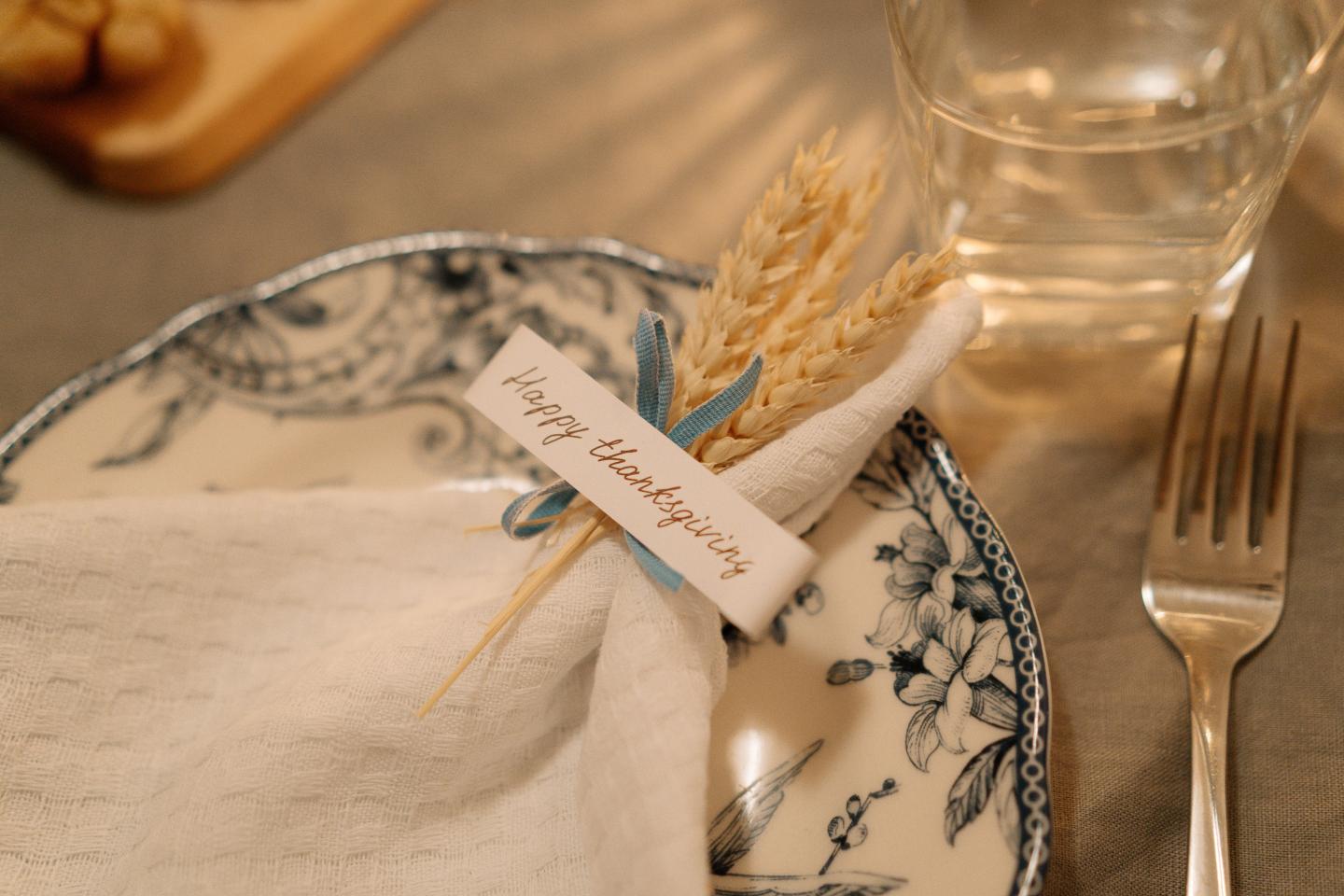 Rustic place setting with floral plate, napkin, wheat sprig, and name card.