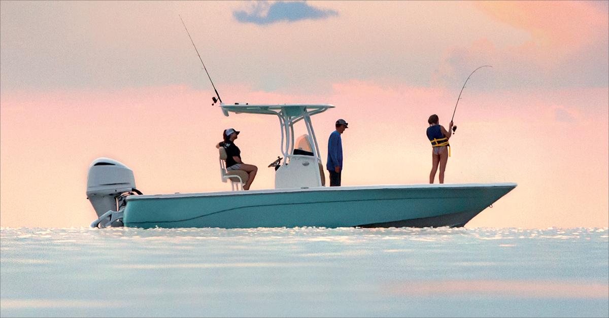 Three people fishing from a small boat on calm water at sunset.