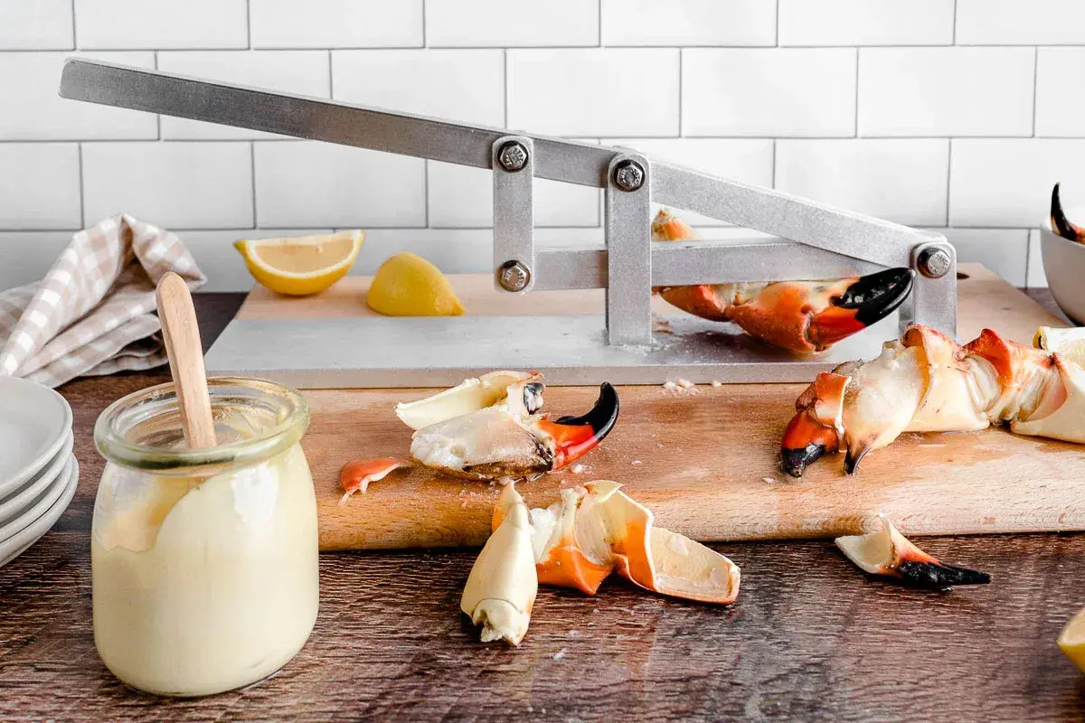 Fresh crab meat, lemon, and sauce jars on a kitchen counter.