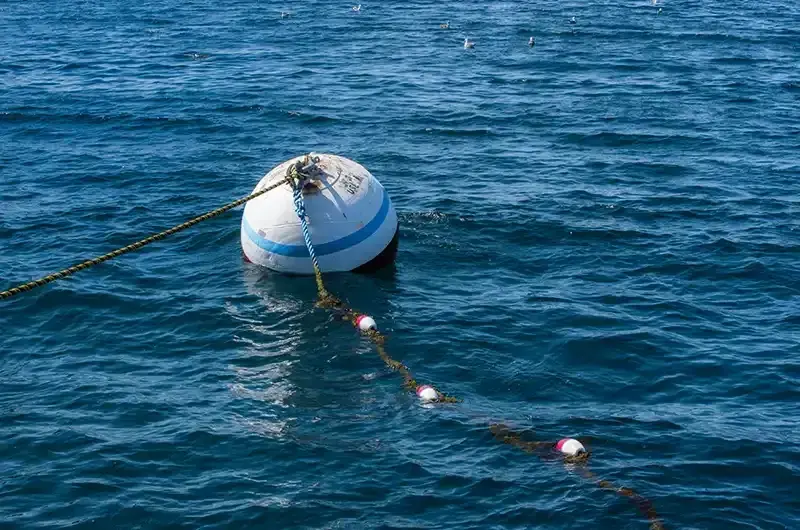 Small blue-and-white buoy tethered in rippling dark blue water.