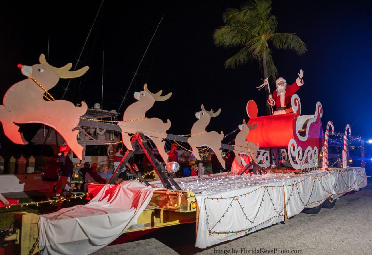 Nighttime Christmas parade float with reindeer, Santa, and glowing lights.