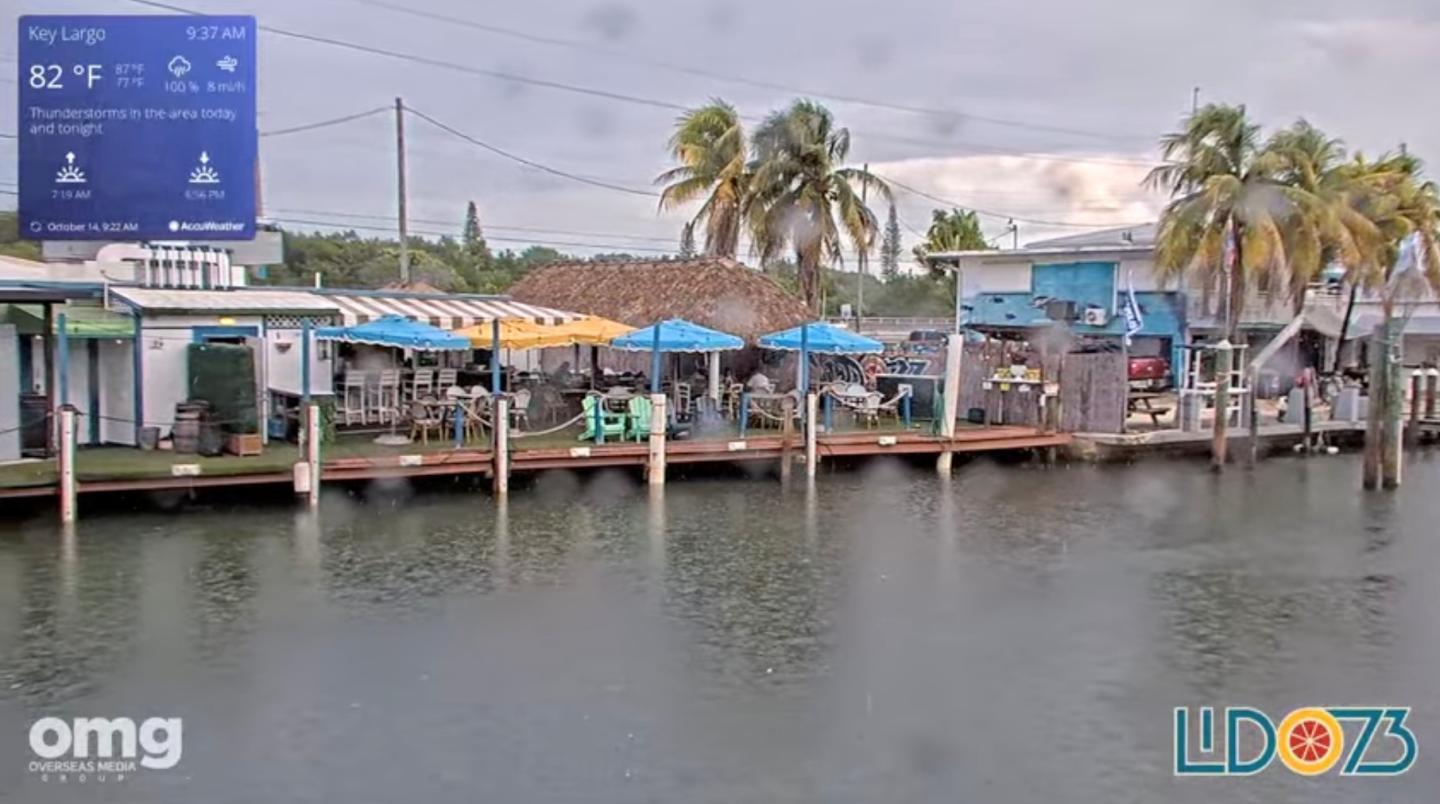 Waterfront shops and boats along a calm canal under a cloudy sky.