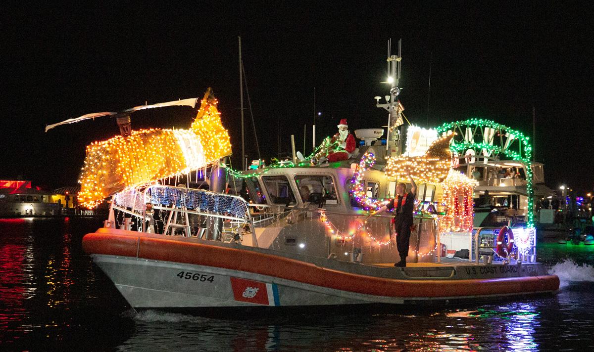 Fishing boat decorated with colorful Christmas lights at night.