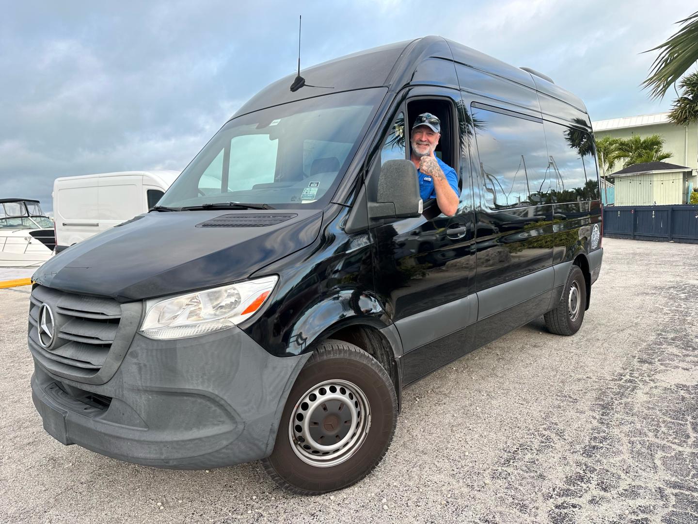 Black Mercedes-Benz cargo van with driver waving from the window.